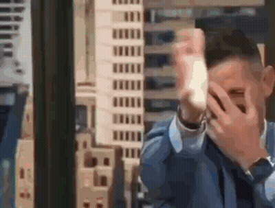 Man In Suit Covering Face Before City Skyline GIF