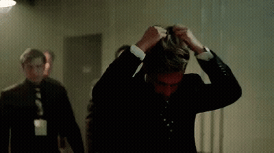 Man In Suit Covering Face While Walking GIF