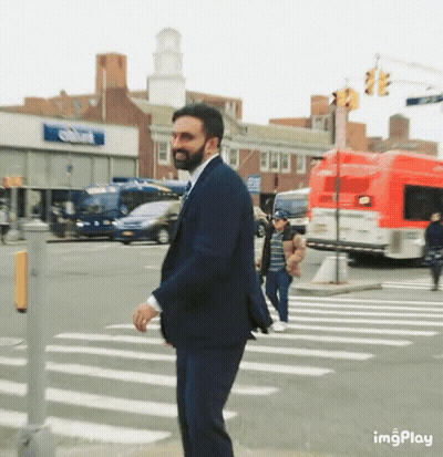 Man In Suit Crossing Street In Front Of Imgplay Building GIF