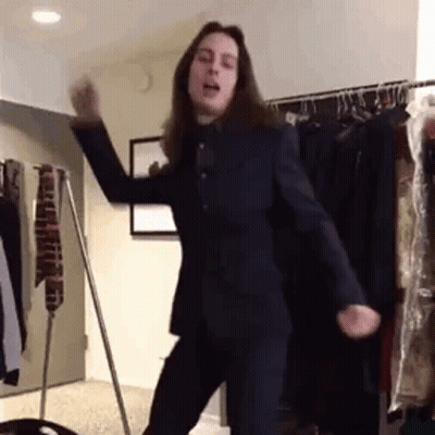 Man In Suit Dancing In Front Of Clothes Rack GIF