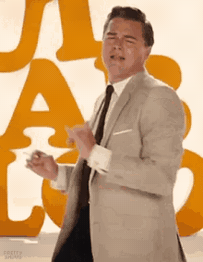 Man In Suit Dancing In Front Of Orange Letter GIF