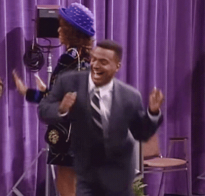 Man In Suit Dancing On Stage With Woman In Blue Hat GIF