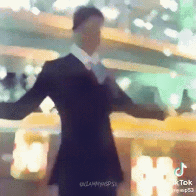 Man In Suit Dancing With Arms Outstretched In Front Of Building GIF