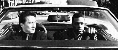 Man In Suit Driving Car With Another Man In Back GIF