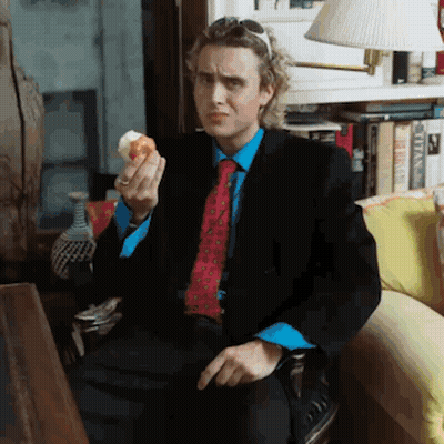 Man In Suit Eating Donut On Couch GIF