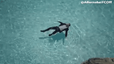 Man In Suit Floating On Back In Pool GIF