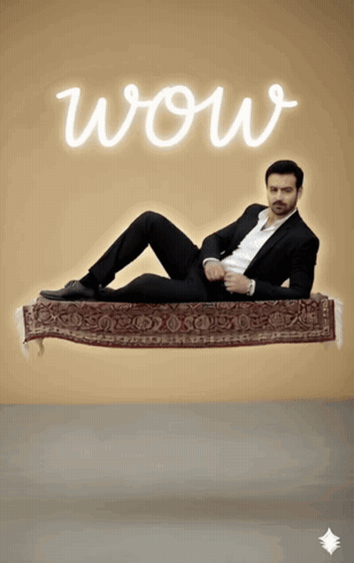 Man In Suit Flying On Rug Saying Wow GIF