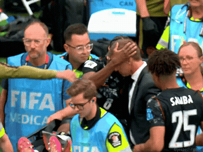 Man In Suit Helped By People In FIFA Vests GIF