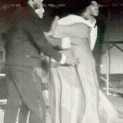 Man In Suit Helping Woman In White Dress With Cane GIF