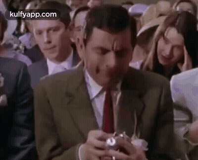 Man In Suit Holding Camera In Crowd GIF