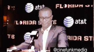 Man In Suit Holding Cell Phone At Microphone GIF