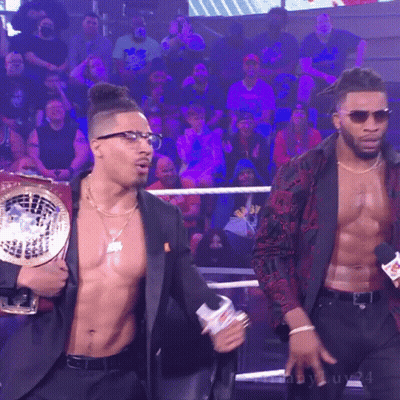 Man In Suit Holding Championship Belt With Another Man Behind GIF