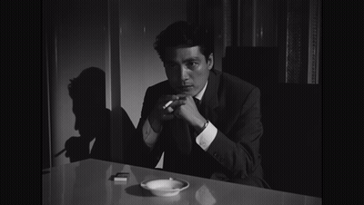Man In Suit Holding Cigarette At Table GIF