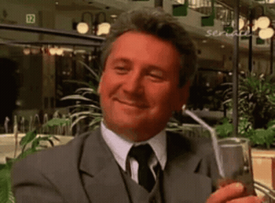 Man In Suit Holding Drink Through Straw Smiling GIF