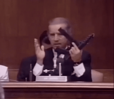 Man In Suit Holding Gun In Courtroom GIF