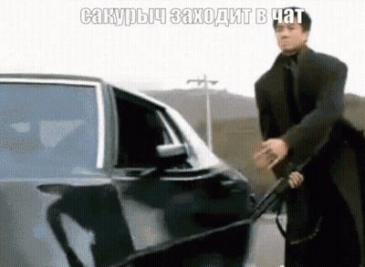 Man In Suit Holding Gun In Front Of Car With Foreign Caption GIF
