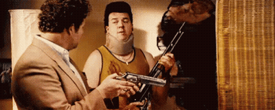 Man In Suit Holding Gun Talking To Another Man Holding Gun GIF