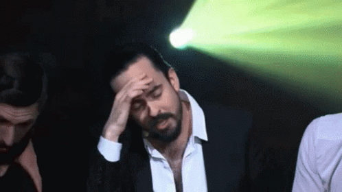Man In Suit Holding Hand To Forehead GIF