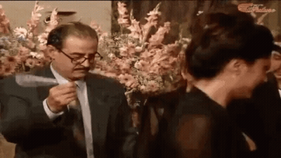 Man In Suit Holding Knife Beside Woman In Black Dress GIF