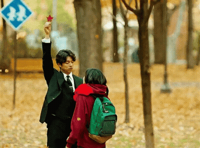 Man In Suit Holding Maple Leaf Over Girl With Green Backpack GIF