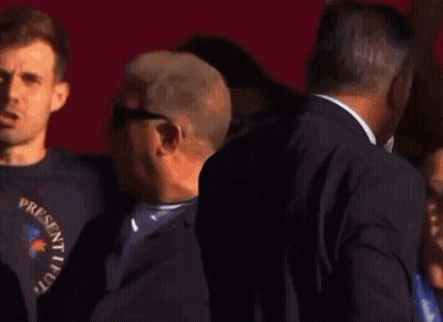 Man In Suit Holding Microphone In Front Of Group GIF