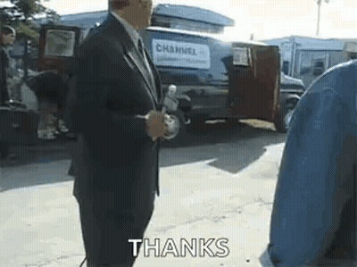 Man In Suit Holding Microphone In Front Of Van Saying Thanks GIF