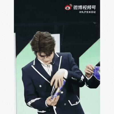 Man In Suit Holding Object With Chinese Writing GIF