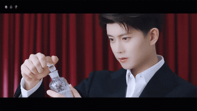 Man In Suit Holding Small Bottle GIF