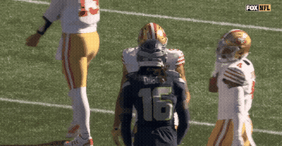 Man In Suit Holding Something By Brick Wall GIF