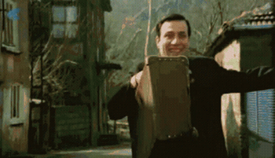 Man In Suit Holding Suitcase Smiling GIF