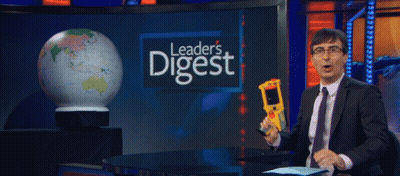 Man In Suit Holding Thermometer In Front Of Leader's Digest Sign GIF