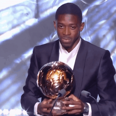 Man In Suit Holding Trophy At Microphones GIF