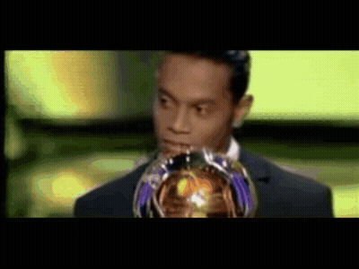 Man In Suit Holding Trophy In Front Of Face GIF