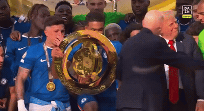 Man In Suit Holding Trophy With Athletes GIF