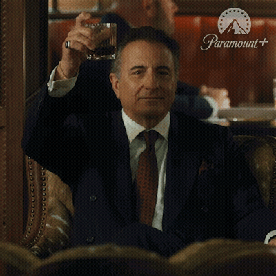 Man In Suit Holding Whiskey In Front Of Paramount Sign GIF