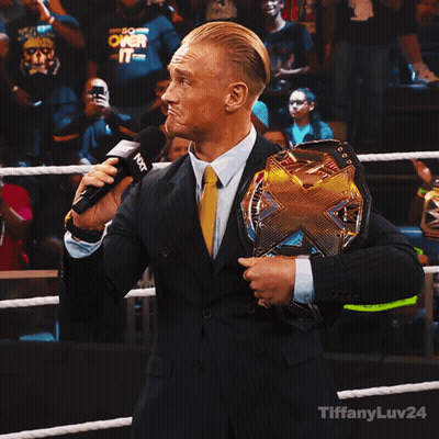 Man In Suit Holding Wrestling Championship Belt Talking Into Microphone GIF