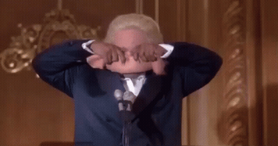 Man In Suit Holds Cloth Over Head Speaking Into Mic GIF