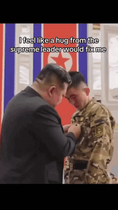 Man In Suit Hugging Man In Military Uniform In Front Of Flag GIF