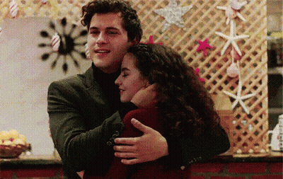 Man In Suit Hugging Woman In Front Of Seashell Wall GIF