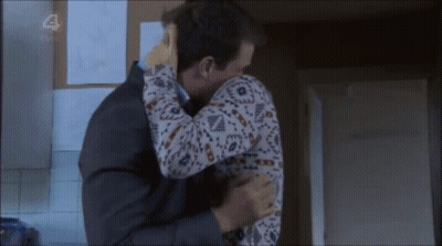 Man In Suit Hugging Woman In Sweater With Number 4 GIF