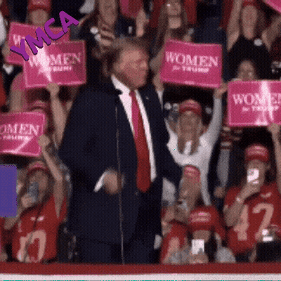 Man In Suit In Front Of Crowd Holding Pink Signs Saying Women GIF