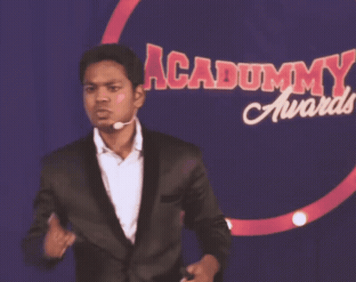 Man In Suit In Front Of Dummy Awards Sign GIF