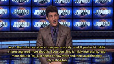 Man In Suit In Front Of Jeopardy Signs GIF