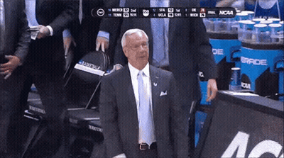Man In Suit In Front Of NCAA Scoreboard GIF