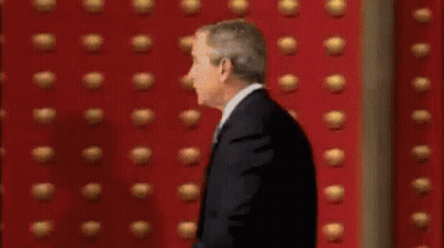 Man In Suit In Front Of Red Wall GIF