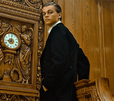 Man In Suit In Front Of Roman Numeral Clock GIF