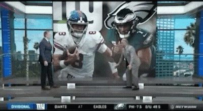 Man In Suit In Front Of Screen With Two Football Players GIF
