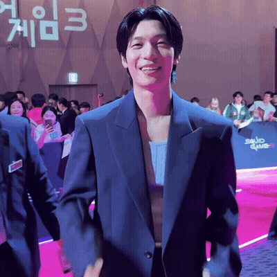 Man In Suit In Front Of Squid Game 3 Sign GIF