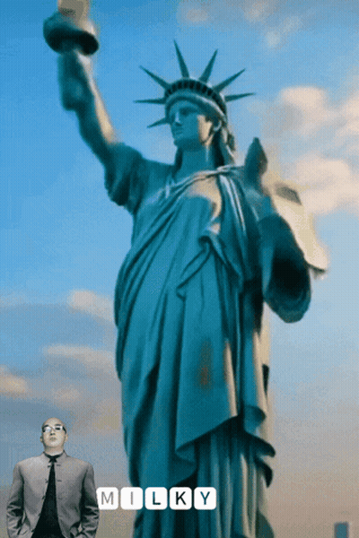Man In Suit In Front Of Statue Of Liberty Saying Milky GIF