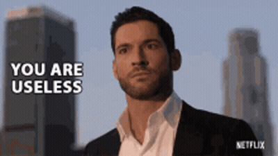 Man In Suit In Front Of Tall Buildings Says You Are Useless GIF